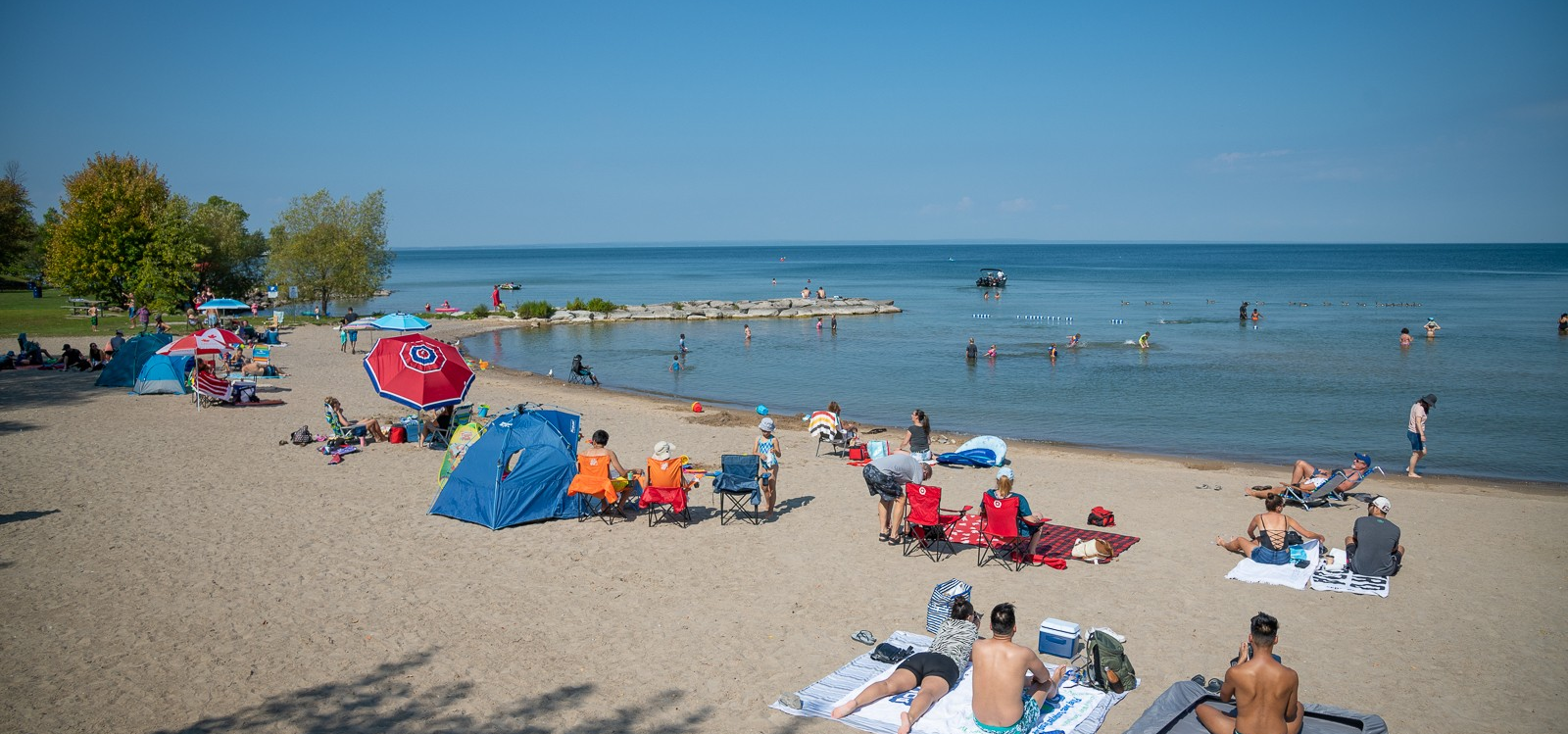 beach view with many groups on the beach sitting on blankets and towels or chairs