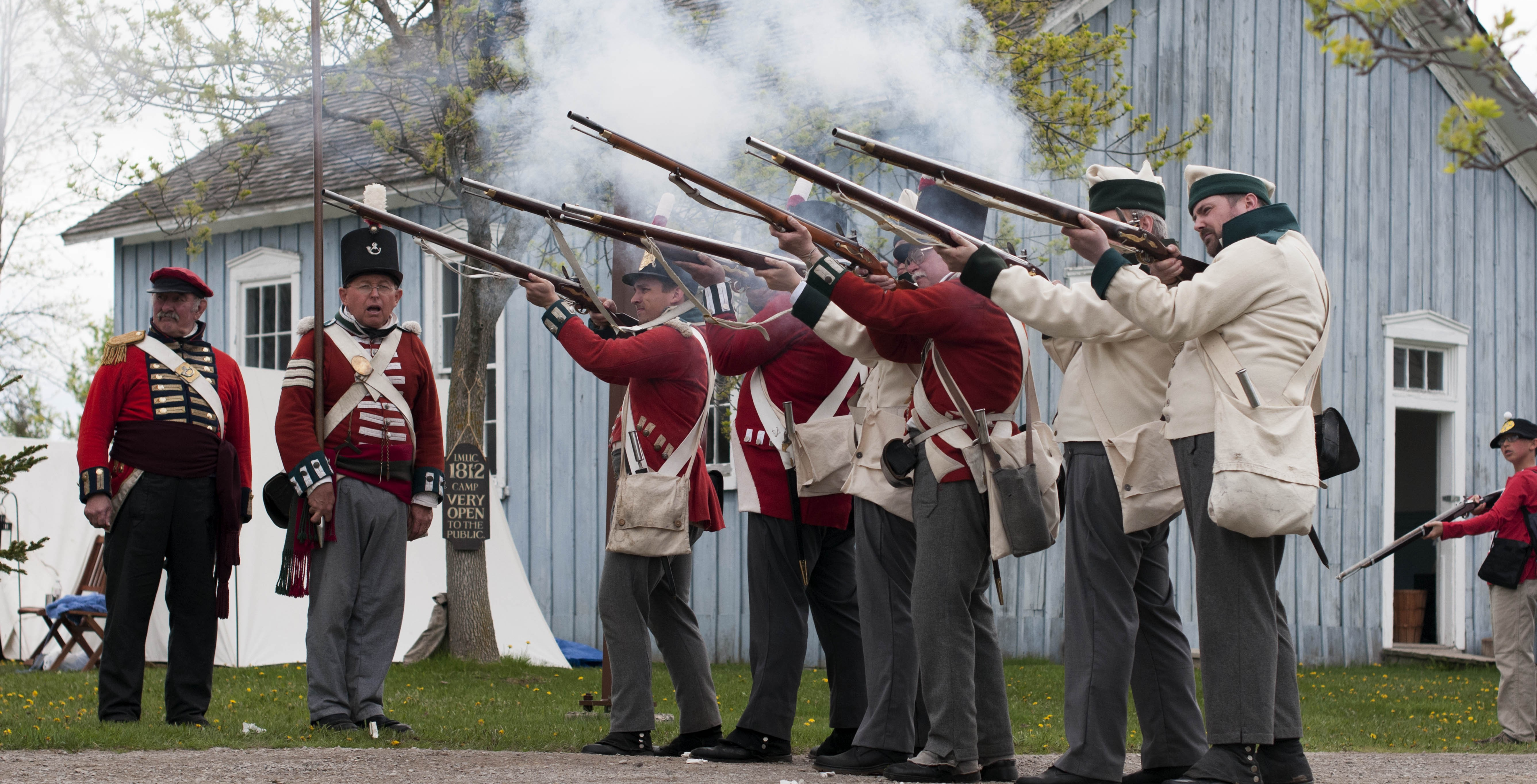 9 men in period soldier dress with muskets