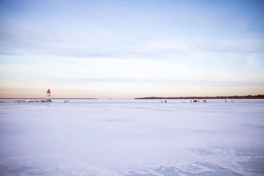 snow covered lake with lighthouse