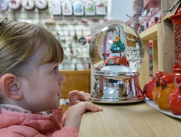 young girl looking at snow globe in shop